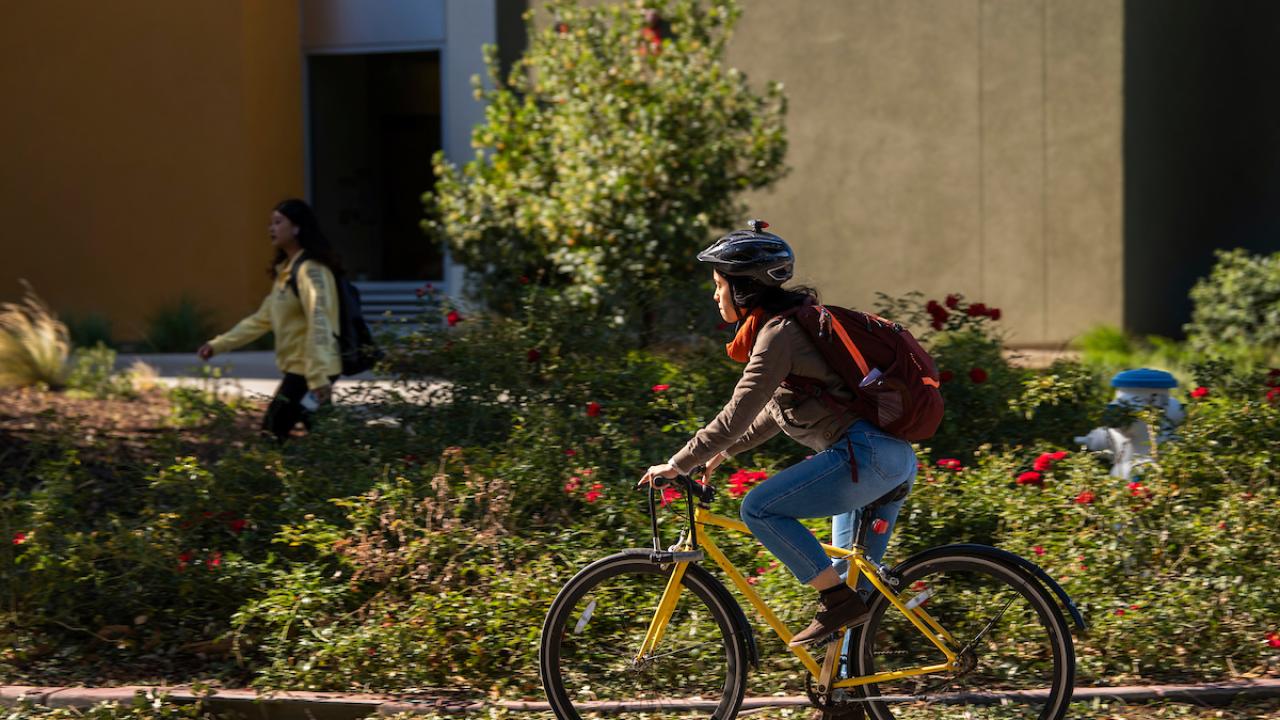 Student wearing helmet on bike.