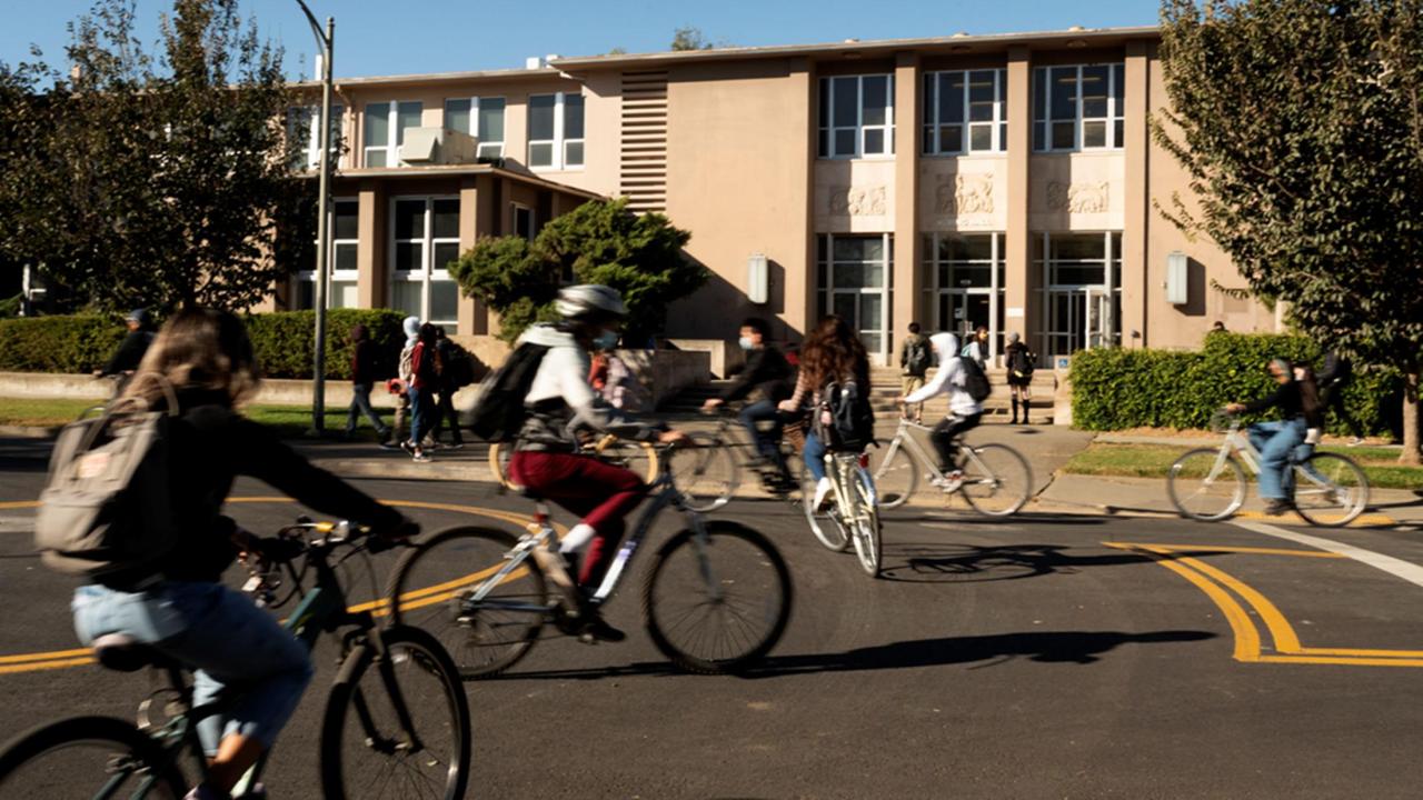 Students on bikes in traffic circle outside Haring Hall